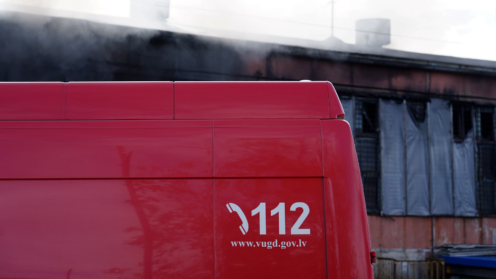 Ugunsdzēsēju mašīna ar numuru 112 pie piedūmotas ēkas
