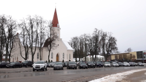Smiltenes baznīca ziemas ainavā ar automašīnām priekšplānā.