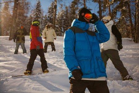 Grupa ar snovbordistem ziemas mežā ar dēļiem gatavojas nobraucienam