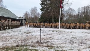 Militārpersonas un jaunieši ceremonijā pie Latvijas karoga ziemas apstākļos.