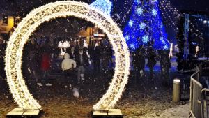 Ziemassvētku dekorācijas un izgaismota egle, cilvēki svin ziemas svētkus sniegotā vakarā