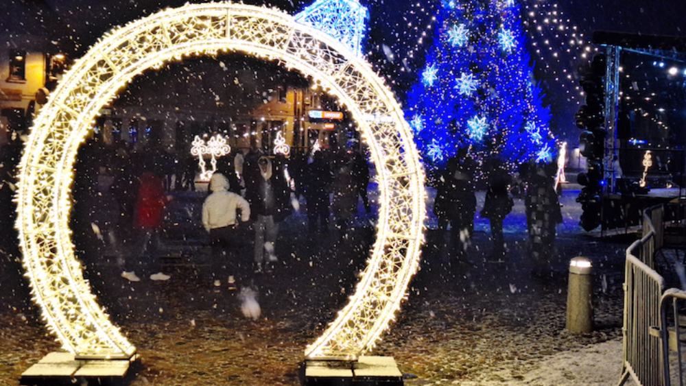 Ziemassvētku dekorācijas un izgaismota egle, cilvēki svin ziemas svētkus sniegotā vakarā