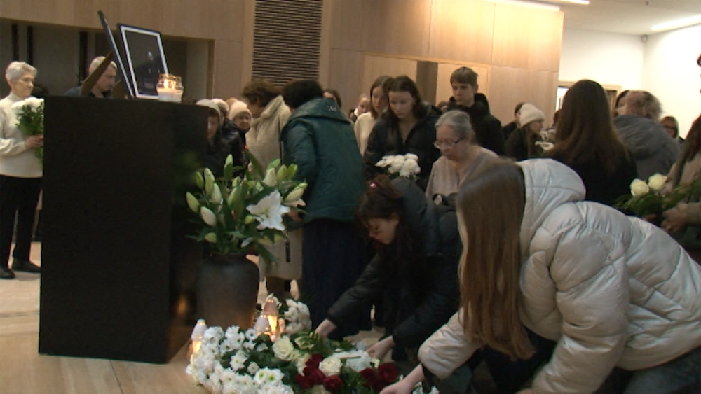 Cilvēki noliek ziedus un aizdedz svecītes piemiņas ceremonijā.