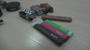 Elektronisko cigarešu ierīces un vienreiz lietojamie e-cigarešu komplekti uz galda.