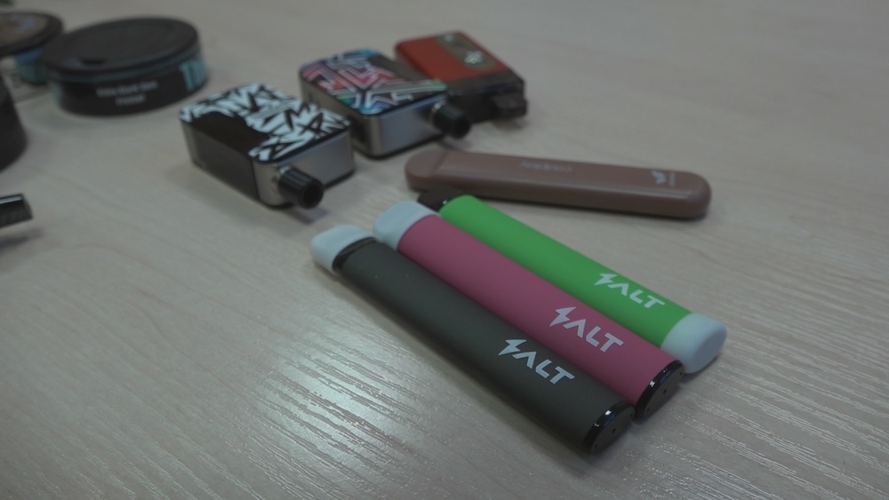 Elektronisko cigarešu ierīces un vienreiz lietojamie e-cigarešu komplekti uz galda.