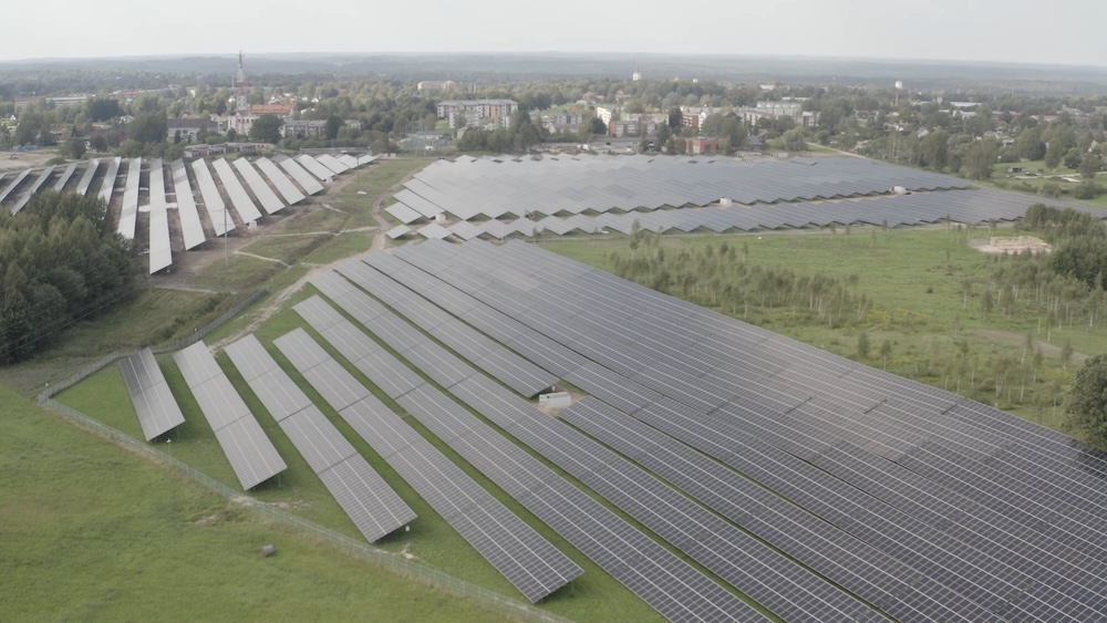 Liels saules paneļu parks Latvijas lauku ainavā.