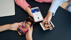 Cilvēki tur mobilos telefonus ar atvērtu "TikTok" aplikāciju.