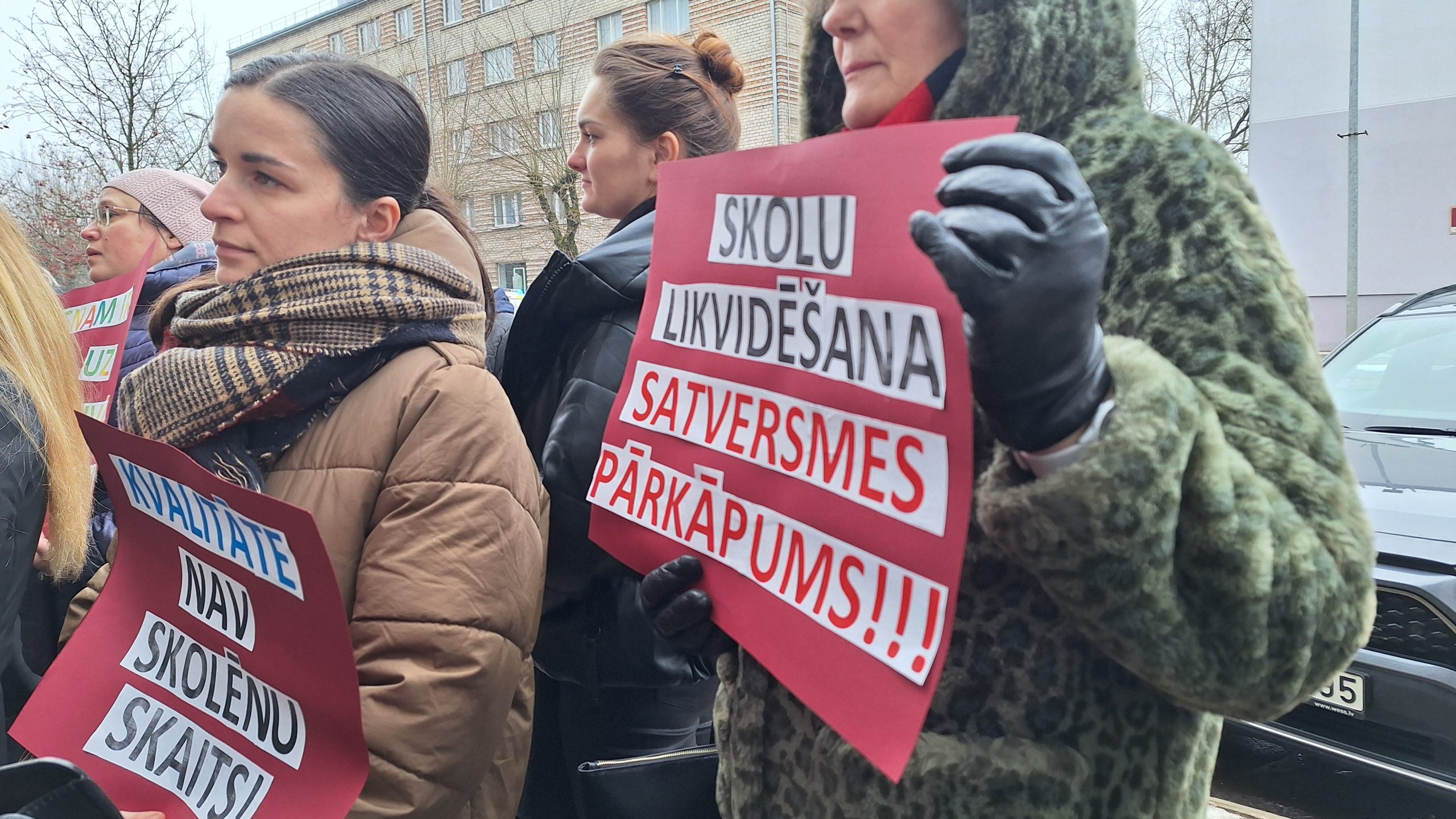 Protestētāji ar plakātiem piketā pret skolu tīkla reformu Elejā.