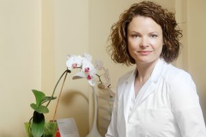 Dr. Vija Veisa savā kabinetā ar orhideju fonā