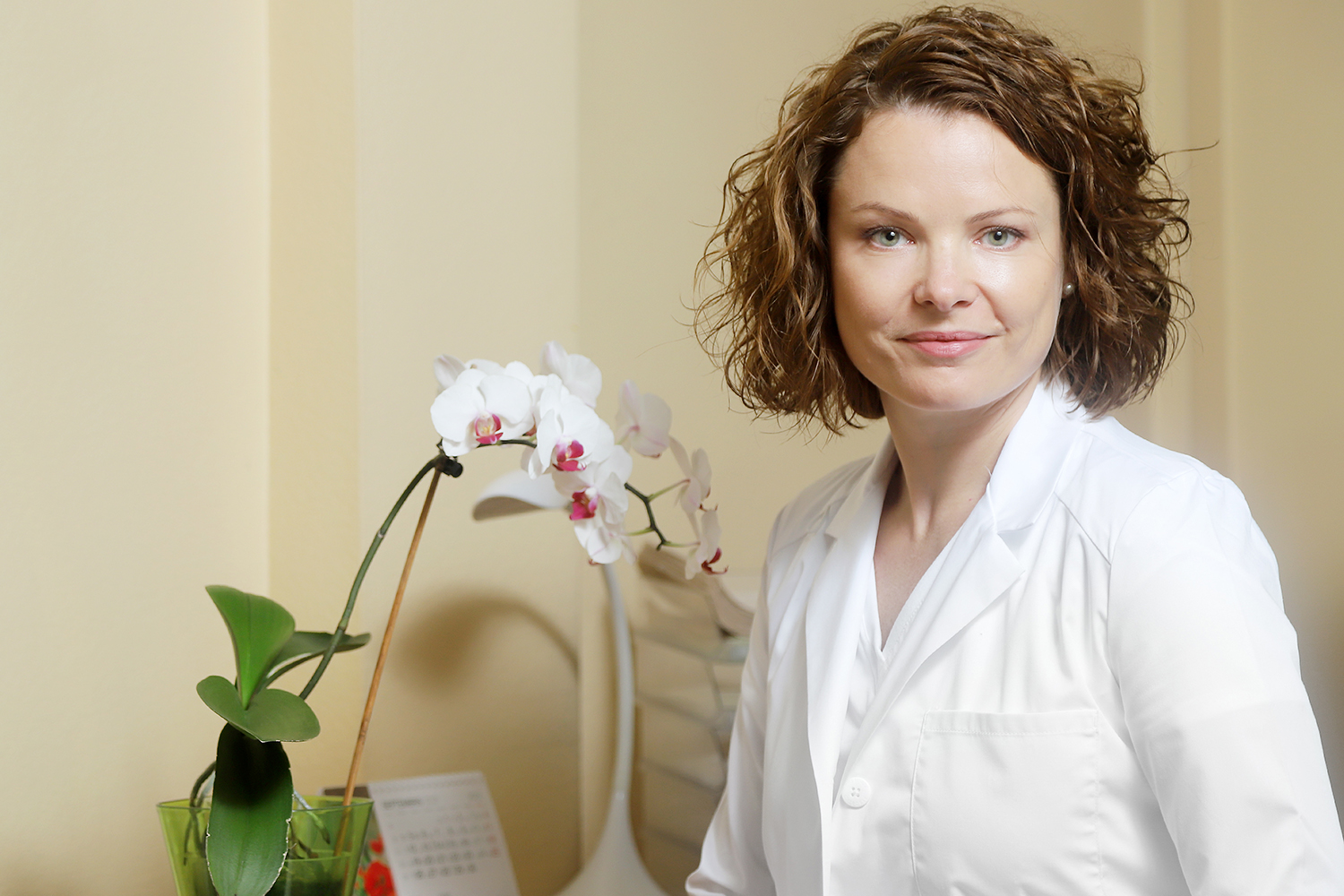 Dr. Vija Veisa savā kabinetā ar orhideju fonā