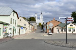 Skaista iela Ludzā ar skatu uz balto baznīcu kalnā, mākoņaina diena.