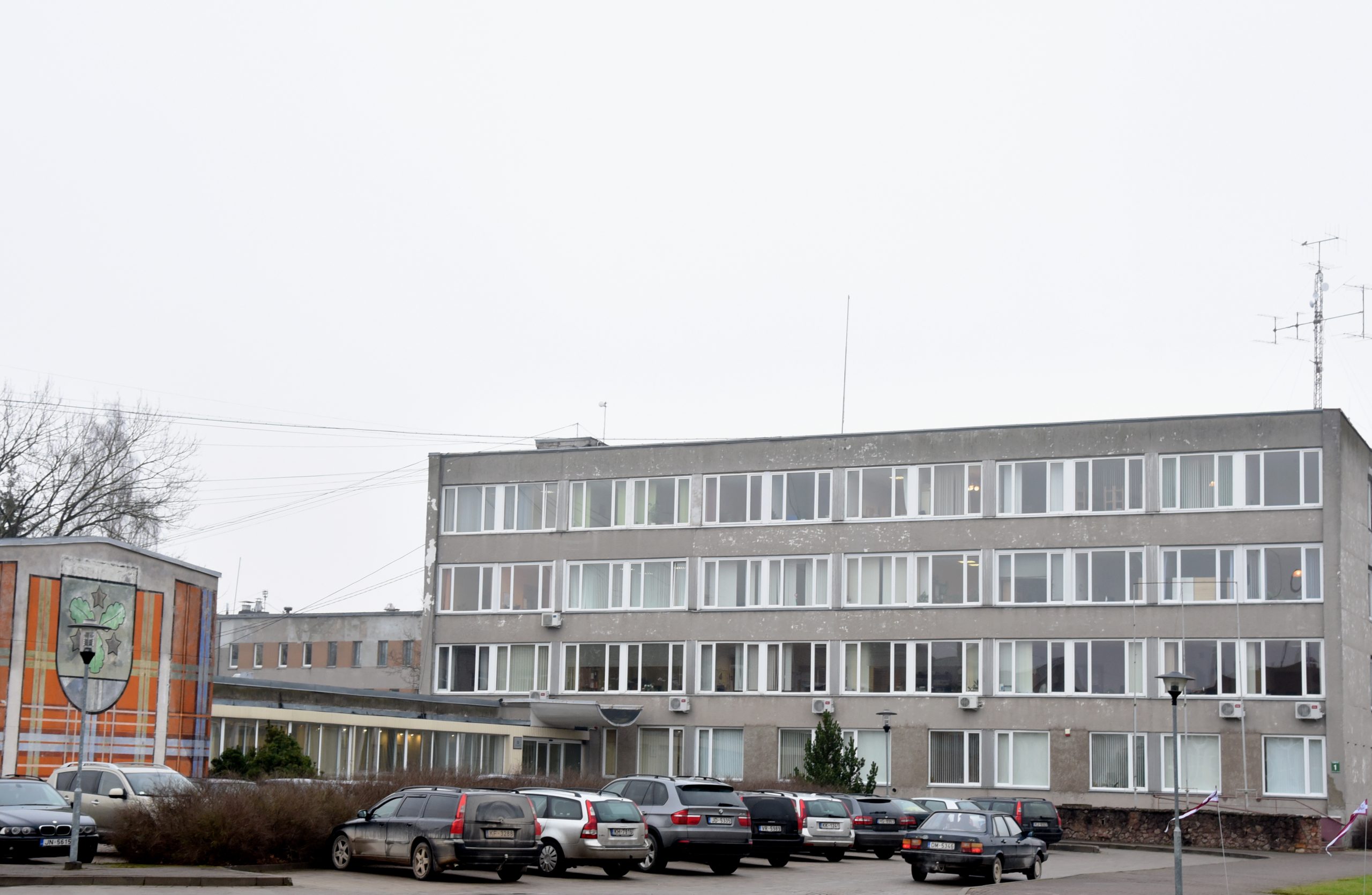 Aizkraukles novada pašvaldības ēka ar automašīnu stāvvietu priekšplānā.