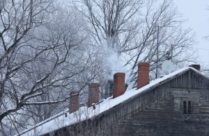 Dūmi paceļas no mājas skursteņiem ziemas laikā.