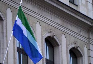 Lībiešu zaļi balti zilais karogs plīvo pie vēsturiskas ēkas fasādes.