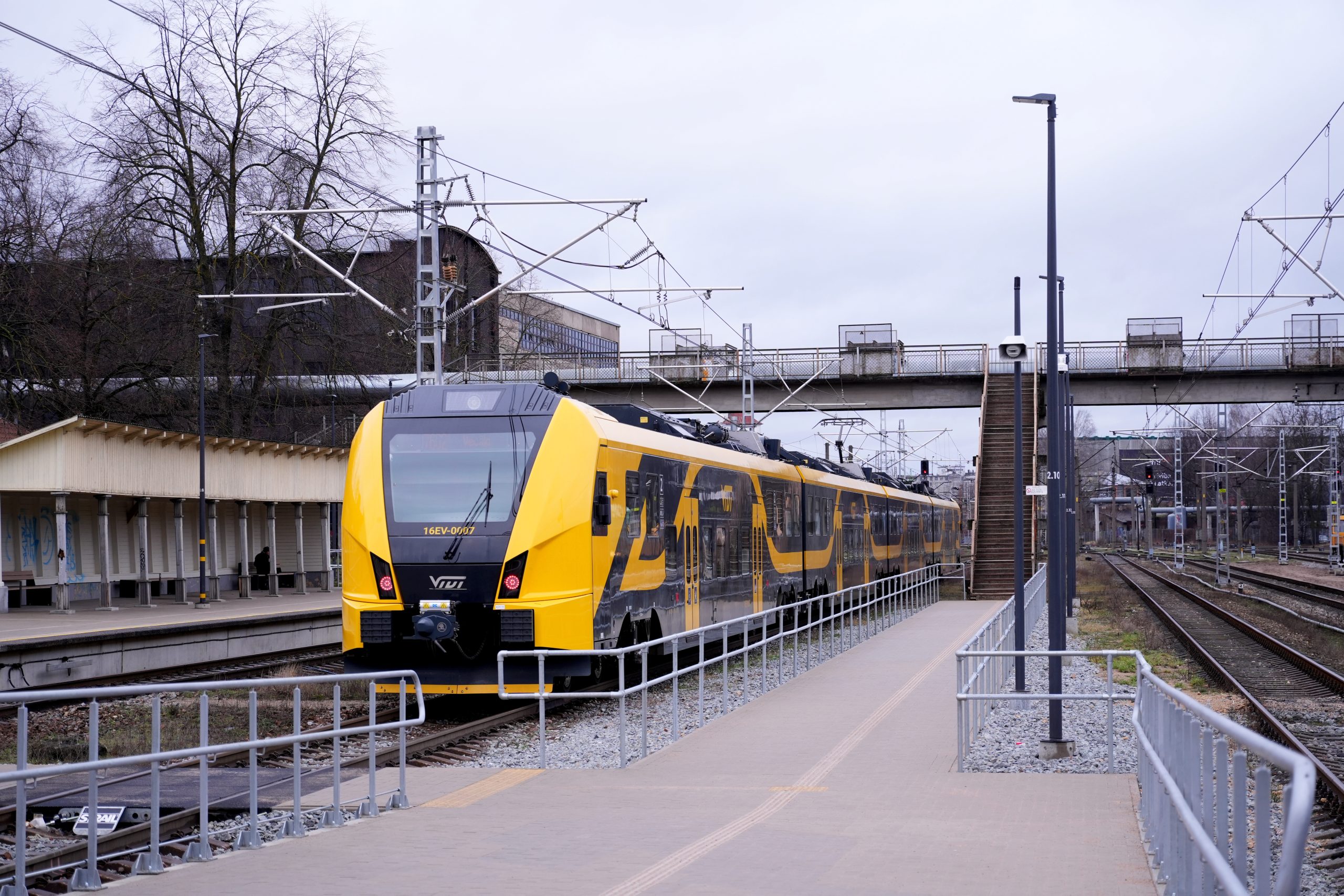 Jauns dzeltenmelns elektrovilciens stacijā uz sliedēm.