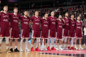 Latvijas basketbola izlase stāv vienotā rindā pirms spēles ar rokām uz pleciem.