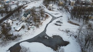 Jēkabpils Pils dīķis ziemā ar sniegotu apkārtni un redzamu ūdens gultni