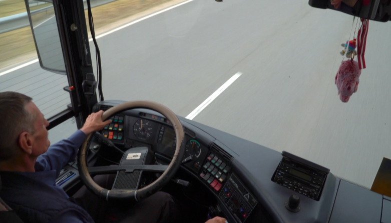 Autobusa vadītājs pie stūres uz šosejas.