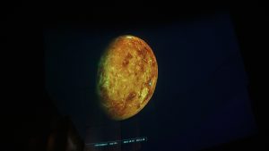 Projekcijā attēlots debess ķermenis, iespējams, asteroīds vai planēta.