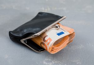 Melna ādas naudas maka atvērums ar sarullētām 50 eiro banknotēm.