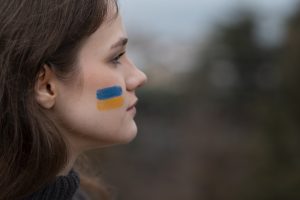 Jauna sieviete ar Ukrainas karoga zīmējumu uz vaiga