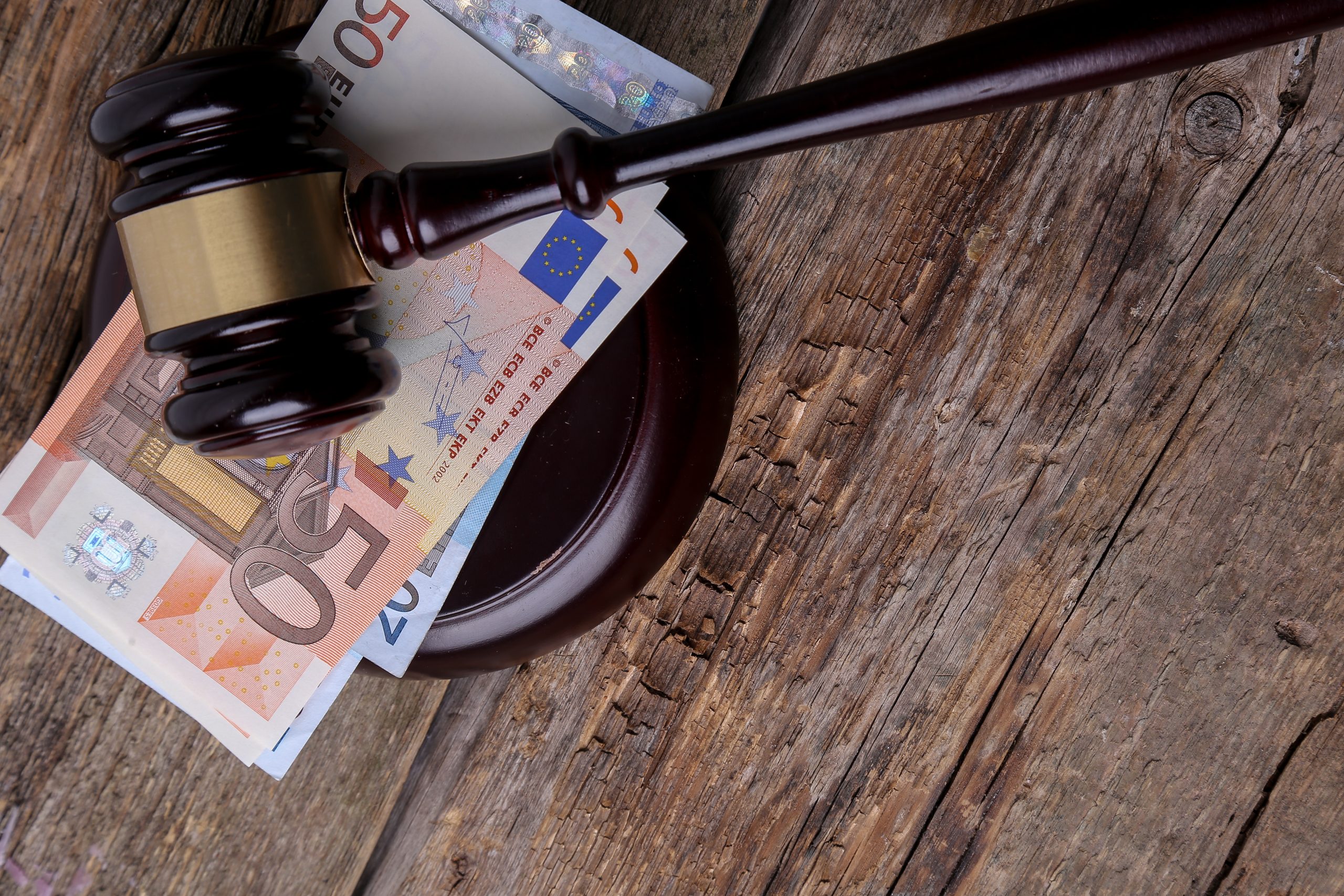 Tiesneša āmurs uz eiro banknotēm koka galda virsmā