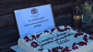 Apliecinājuma diploms "Latvijas Jauniešu galvaspilsēta 2025" Liepājai un svinīga torte ar ogām