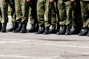 Militārie rezervisti formās un zābakos stāv uz laukuma
