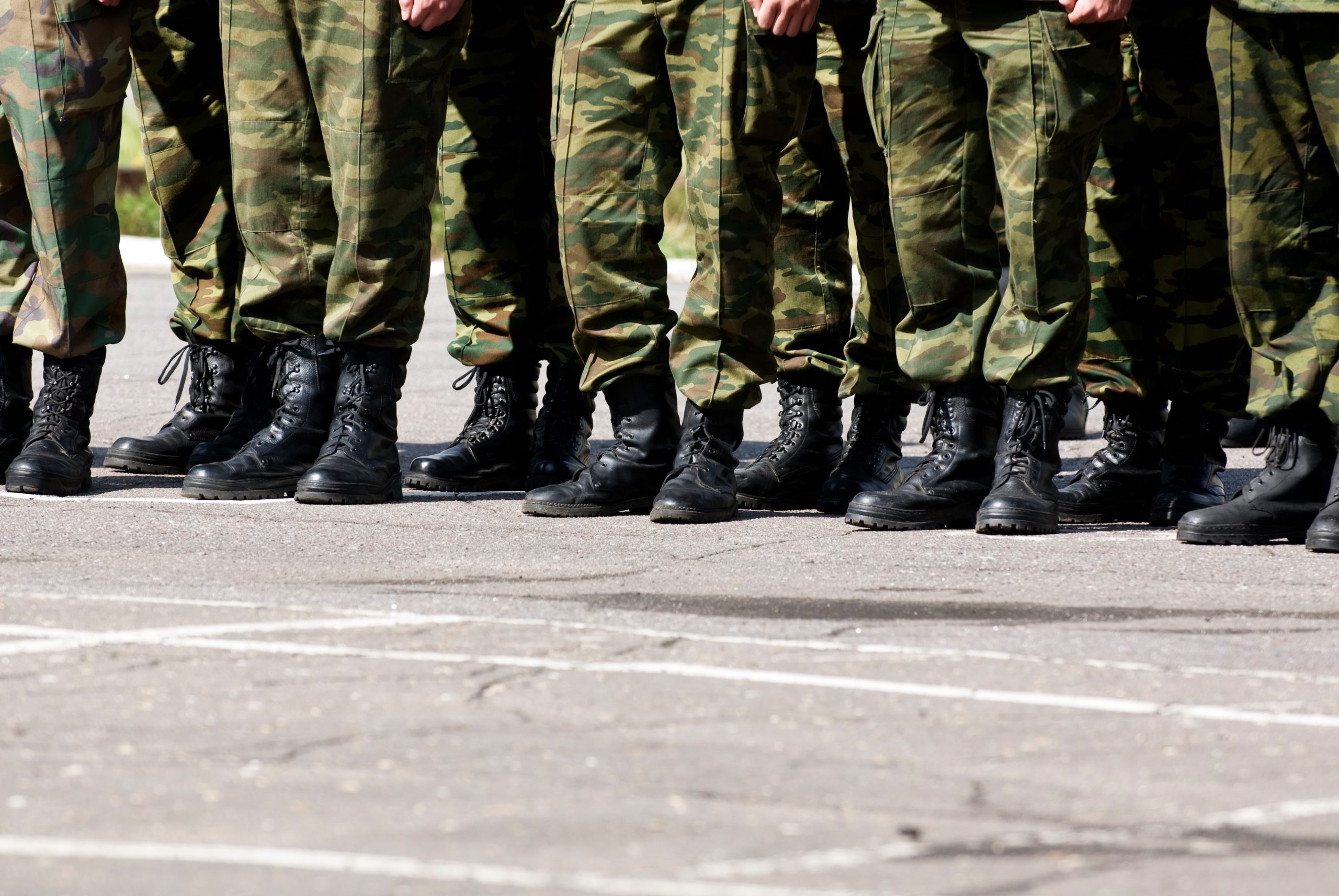 Militārie rezervisti formās un zābakos stāv uz laukuma