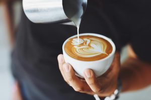 Barista lej pienu krūzē, veidojot latte art rakstu