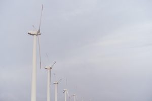 Vēja turbīnas ražo elektroenerģiju pelēkās debesīs