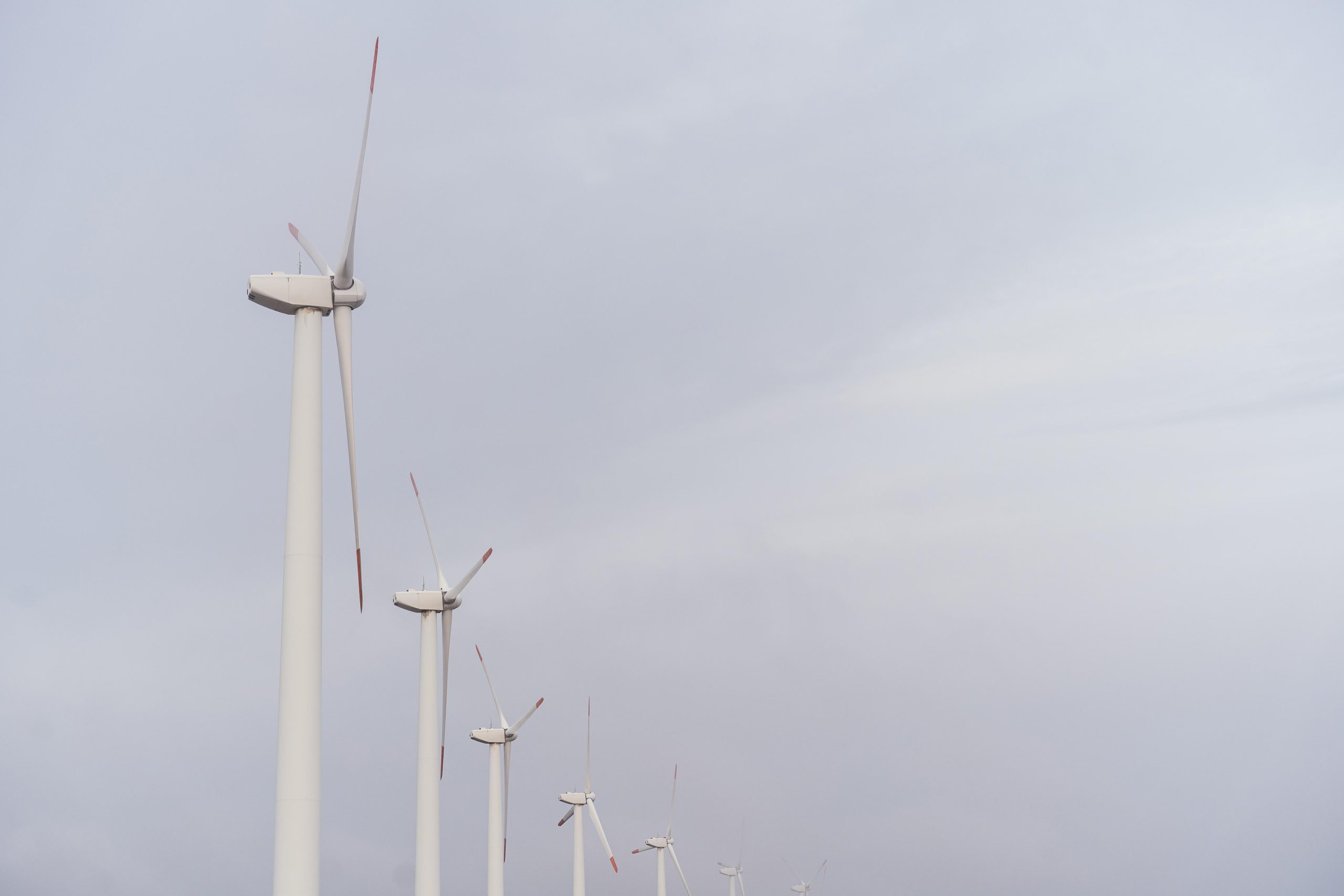 Vēja turbīnas ražo elektroenerģiju pelēkās debesīs