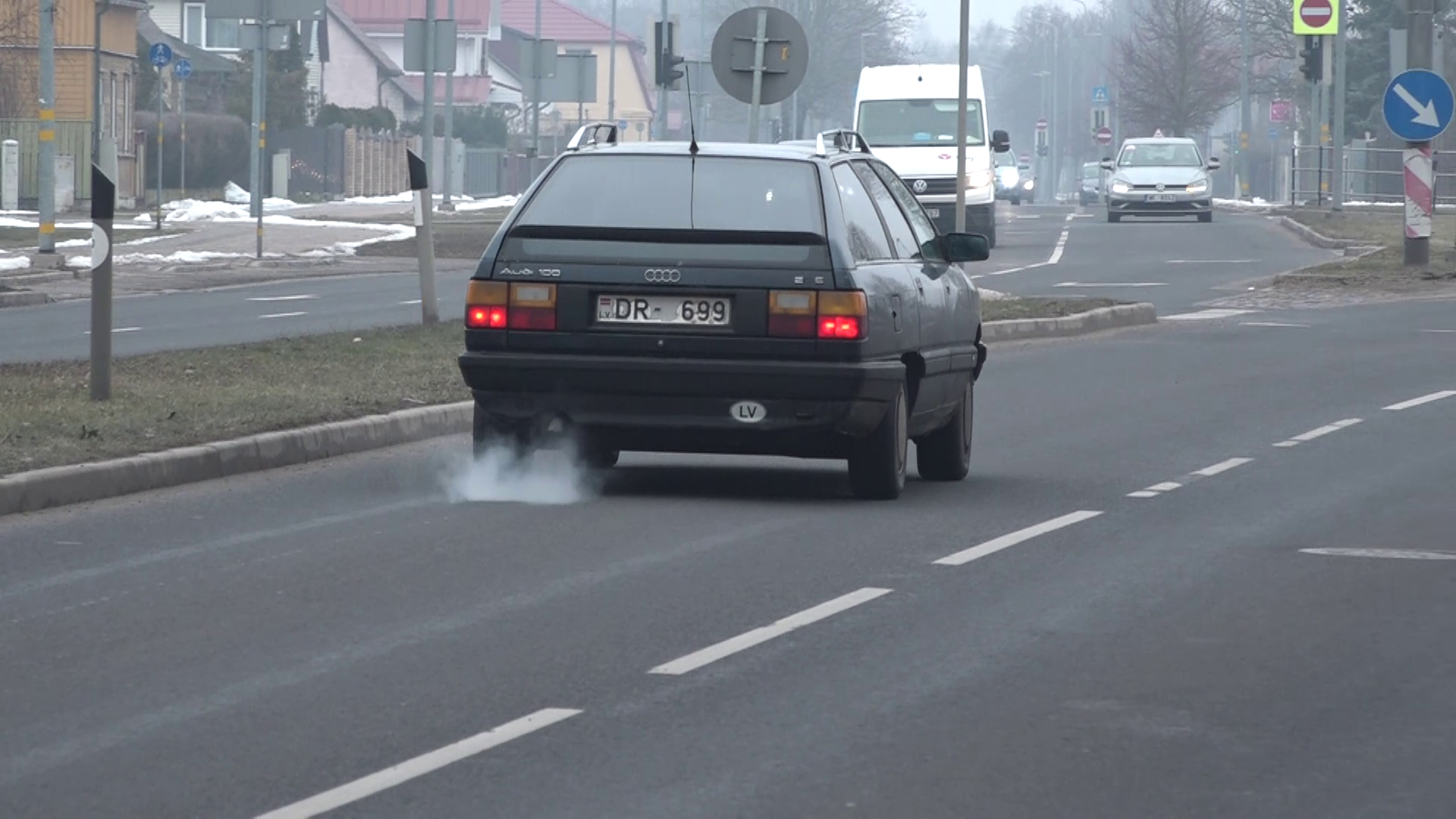 Veca Audi automašīna uz ielas ar redzamiem izplūdes dūmiem.