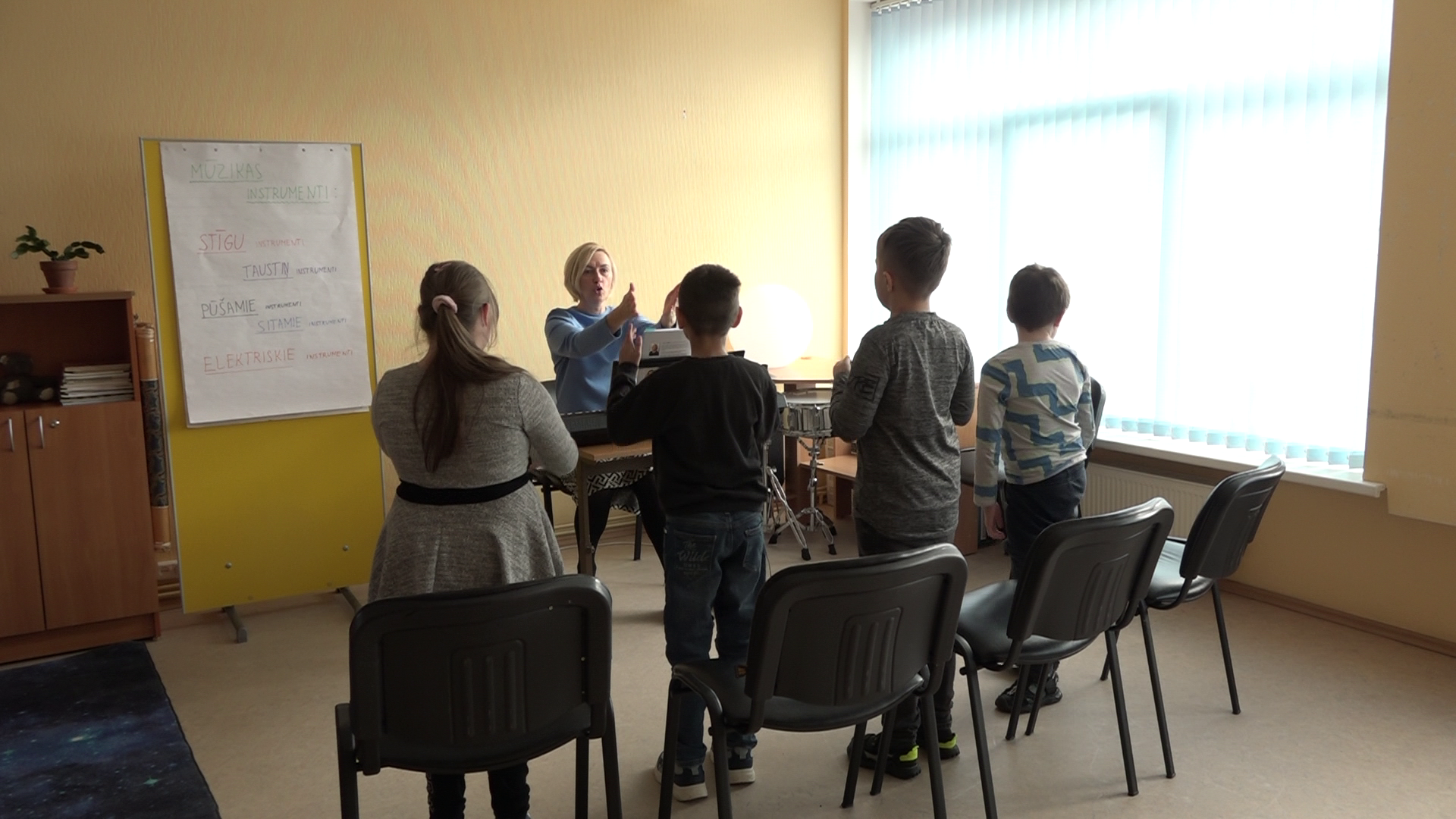 Skolotāja vada mūzikas nodarbību bērniem speciālās izglītības iestādē.