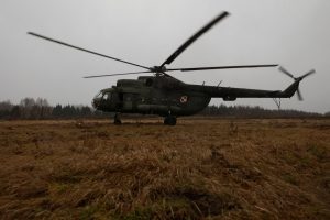 Militārais helikopters lauka apstākļos, zemas debesu apgaismojuma apstākļos