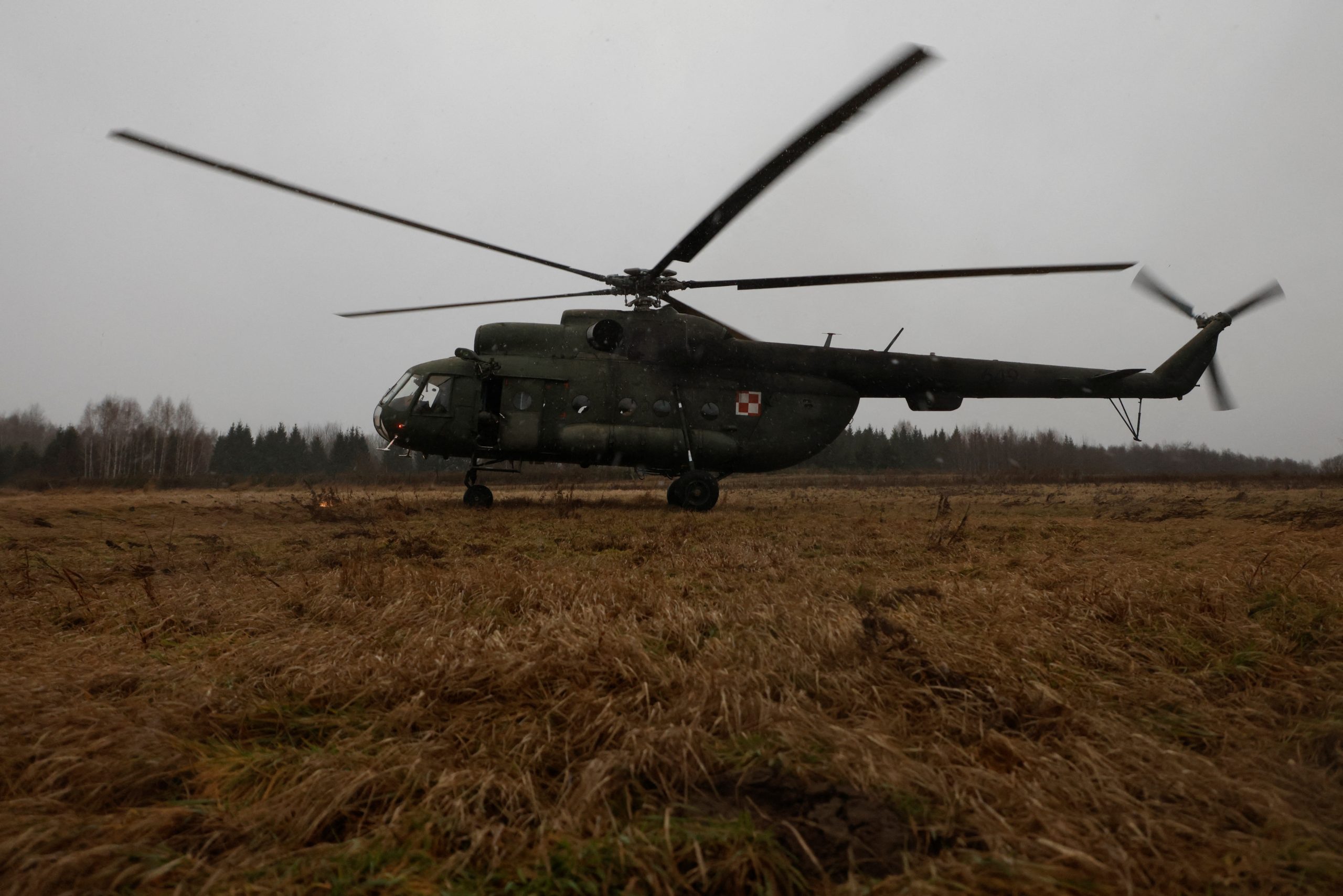 Militārais helikopters lauka apstākļos, zemas debesu apgaismojuma apstākļos