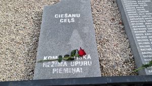 Piemiņas plāksne ar uzrakstu "CIEŠANU CEĻŠ" un sarkanā roze uz tās, godinot komunistiskā režīma upurus.