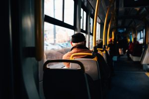 Sirmgalvis sēž sabiedriskajā transportā un skatās pa logu, apkārt citi pasažieri