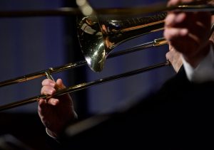Trombonists, kurš spēlē zelta krāsas trombonu uz skatuves