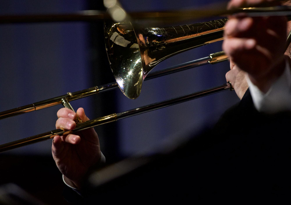 Trombonists, kurš spēlē zelta krāsas trombonu uz skatuves
