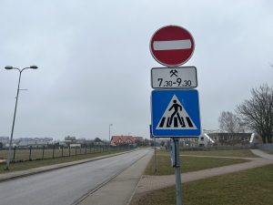 Ceļazīmes ar "Iebraukt aizliegts" un gājēju pārejas norādi uz ielas pie skolas.