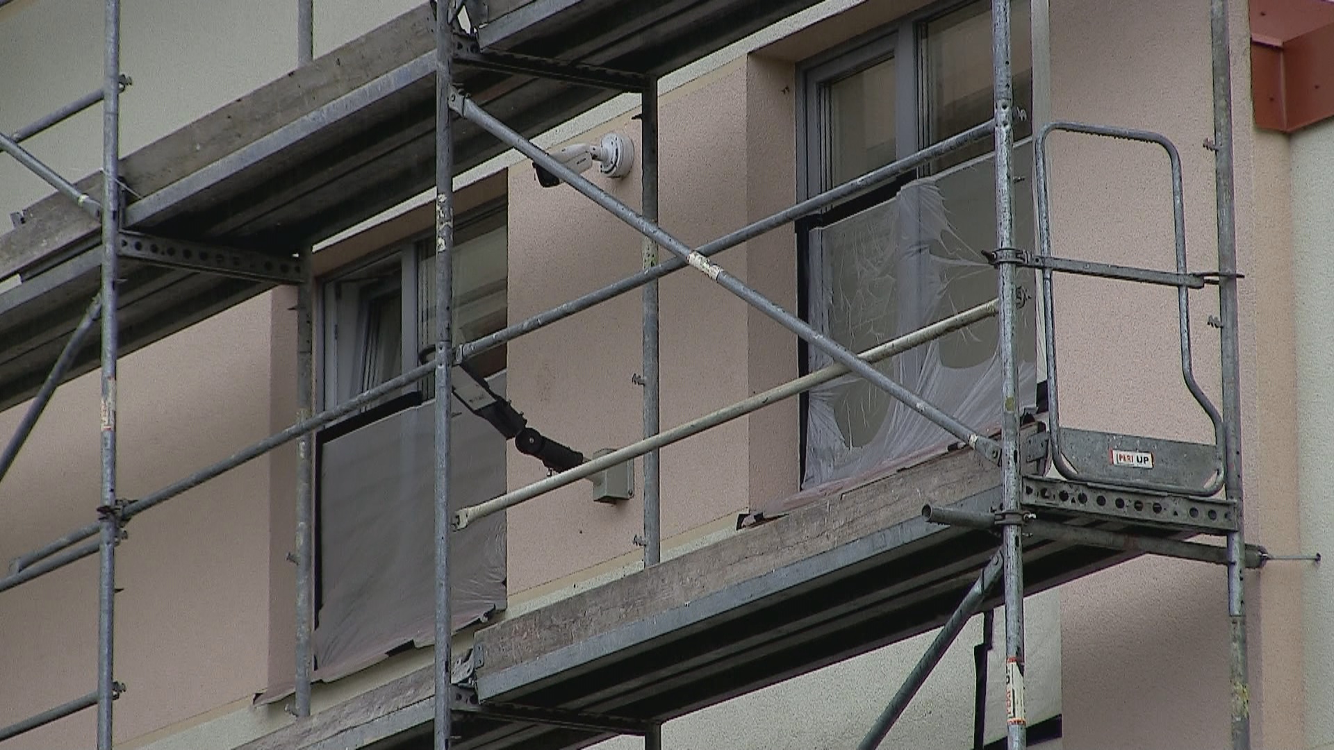Renovācijas procesā esoša ēka ar sastatnēm un aizsargplēvēm uz logiem.