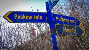 Ceļa zīmes ar uzrakstu Puškina iela, pavasara ainava fonā