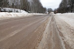 Sniegots lauku autoceļš ar apledojumu un ceļa zīmēm ziemas apstākļos.