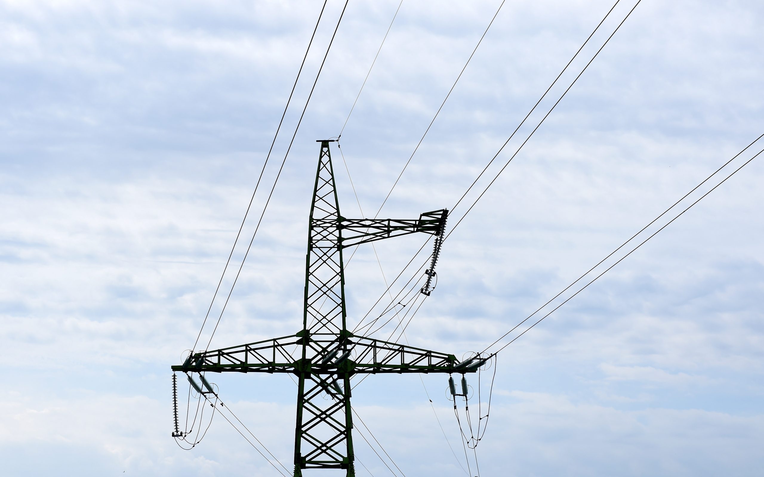 Augstsprieguma elektropārvades līnijas tornis ar elektrības vadiem uz mākoņaina debesu fona