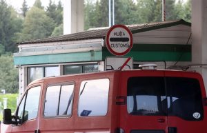Latvijas muitas kontroles punkts ar sarkanu mikroautobusu pie robežas.