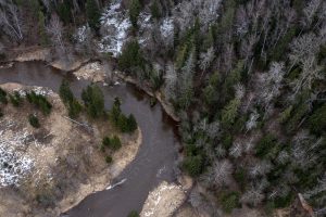 Meandru upe Latvijas mežā no putna lidojuma ziemas beigās.