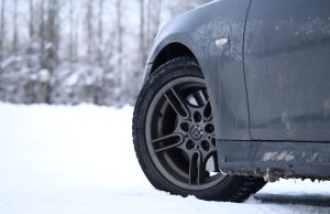 Auto riepa un disks ziemas apstākļos ar sniegu fonā