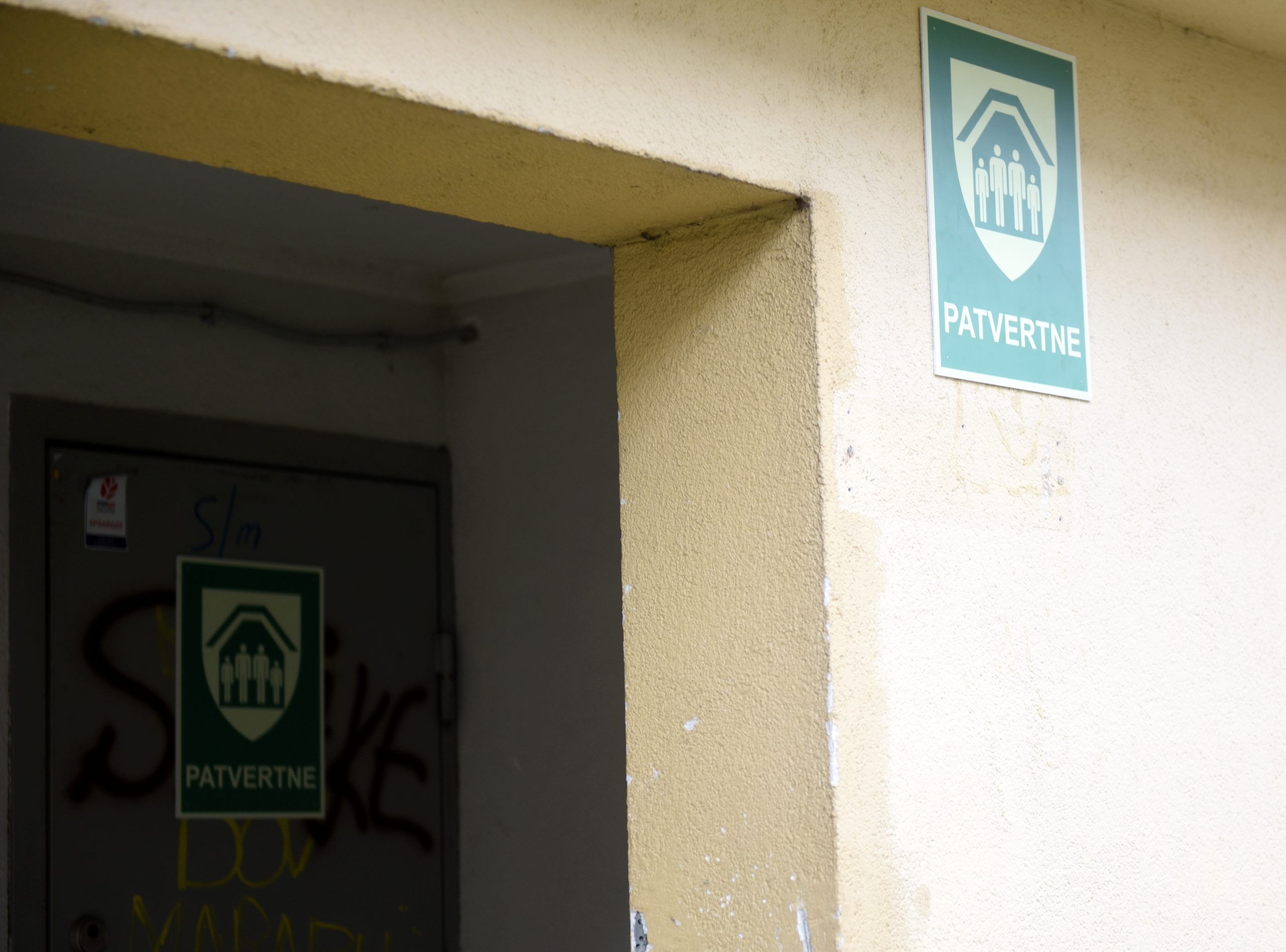 Patvertne daudzdzīvokļu mājas pagrabā ar norādes zīmi uz sienas.