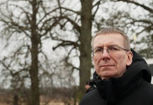 Latvijas Valsts prezidents ziemas apģērbā ārā, fona koki un pelēkas debesis